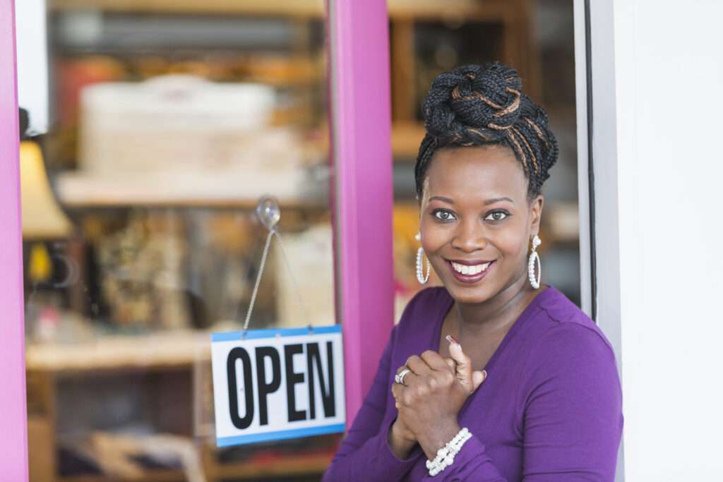 woman in front of small business open sign