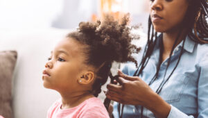 Woman braiding child's hair
